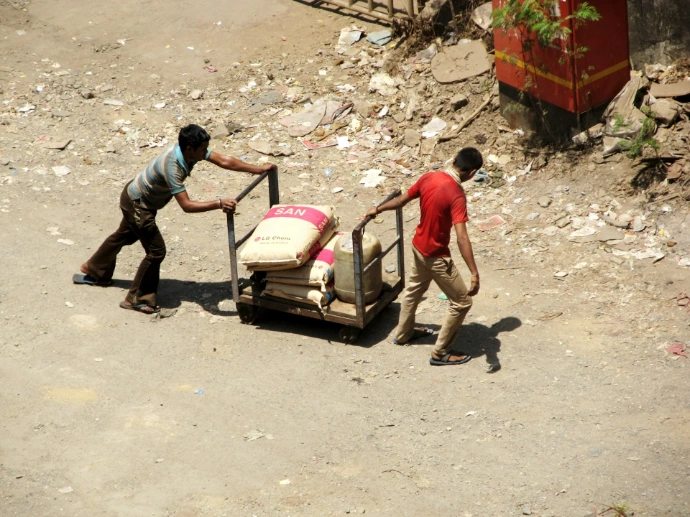 A couple of men pushing a cart down a dirt road